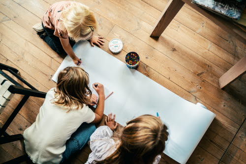 Children drawing on a large sheet of paper