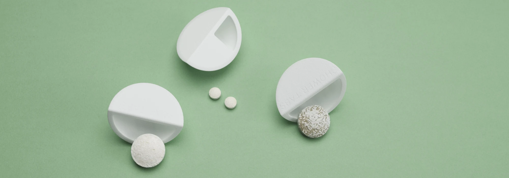 White wood-based packaging with dissolvable tablets on green background
