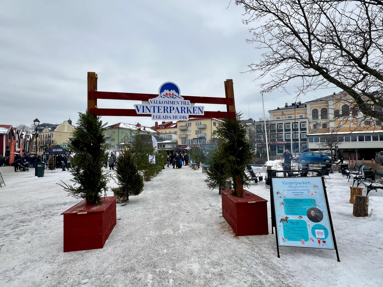 Skylt om Vinterparken i Hudiksvall med stadsmiljö och besökare i bakgrunden.