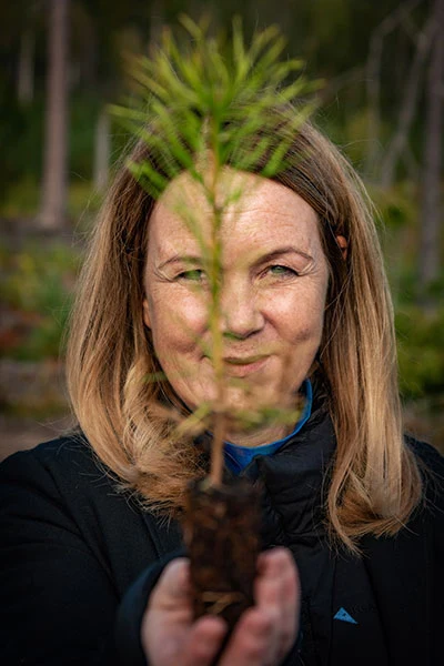 Landsbygdsminister Jennie Nilsson håller upp en tallplanta under ett besök i Holmens skog.