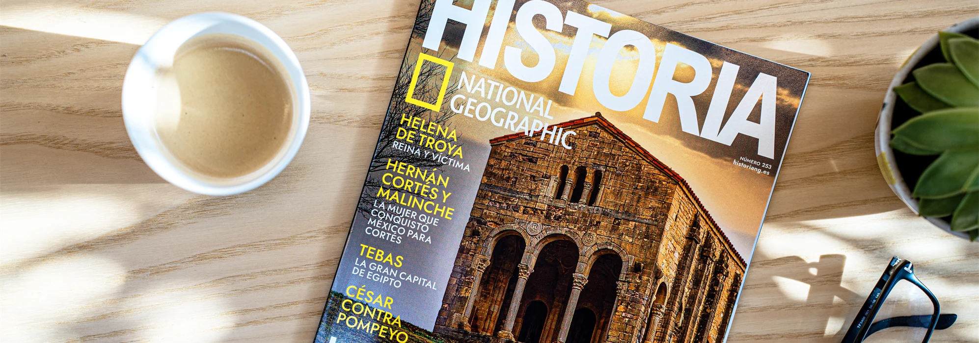 Cover of National Geographics magazine placed on a table with glasses and cup of coffee