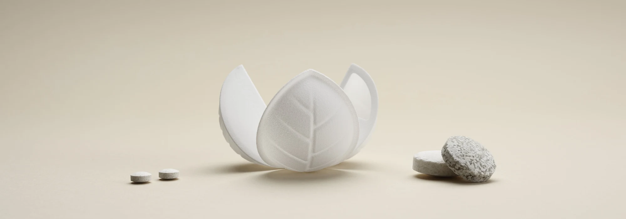 Flowerlike wood-based packaging on beige background, dissolvable tablets spread out around it