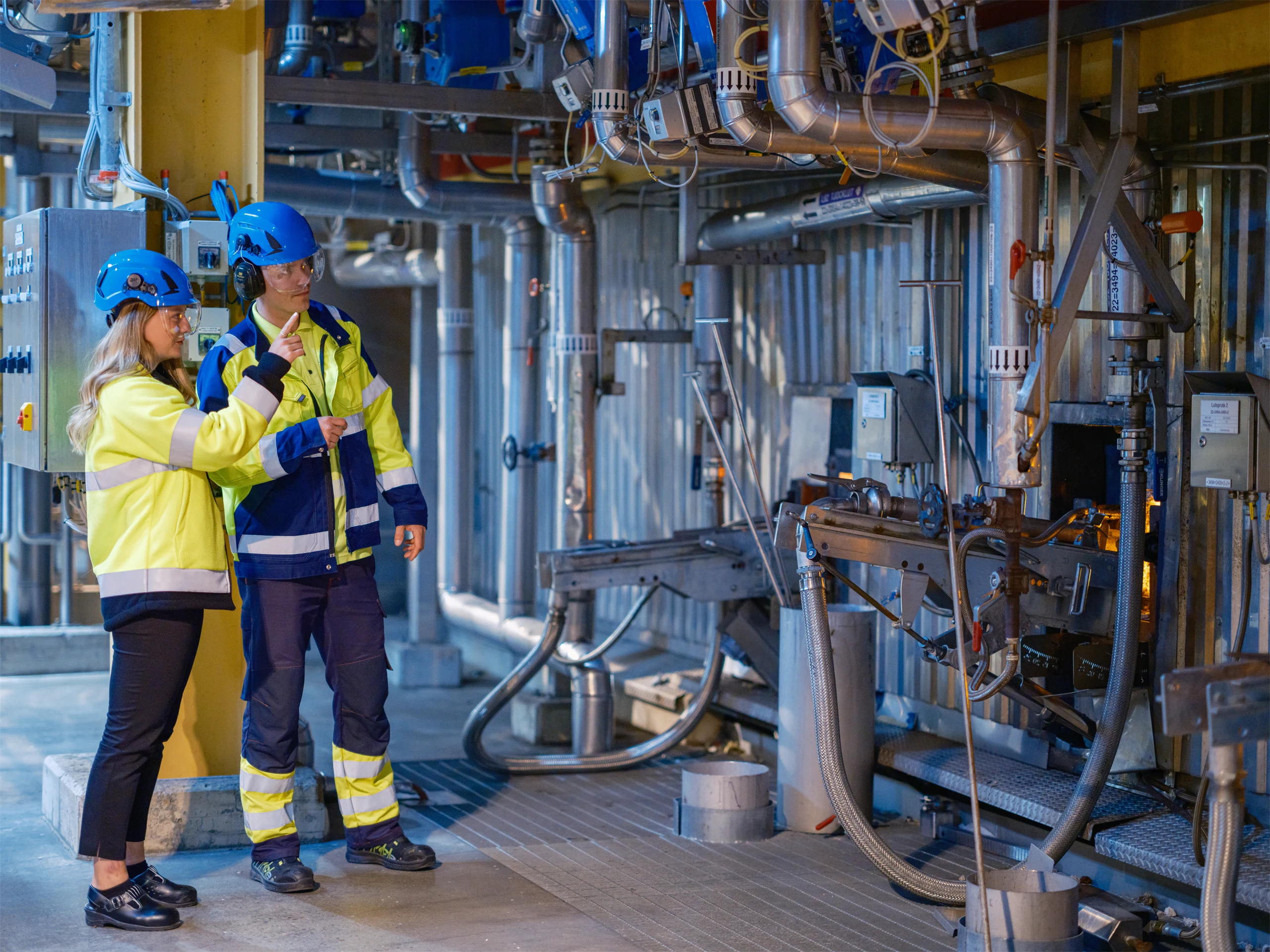 Bild på samarbete mellan två kollegor vid maskin i Holmens industriella miljö
