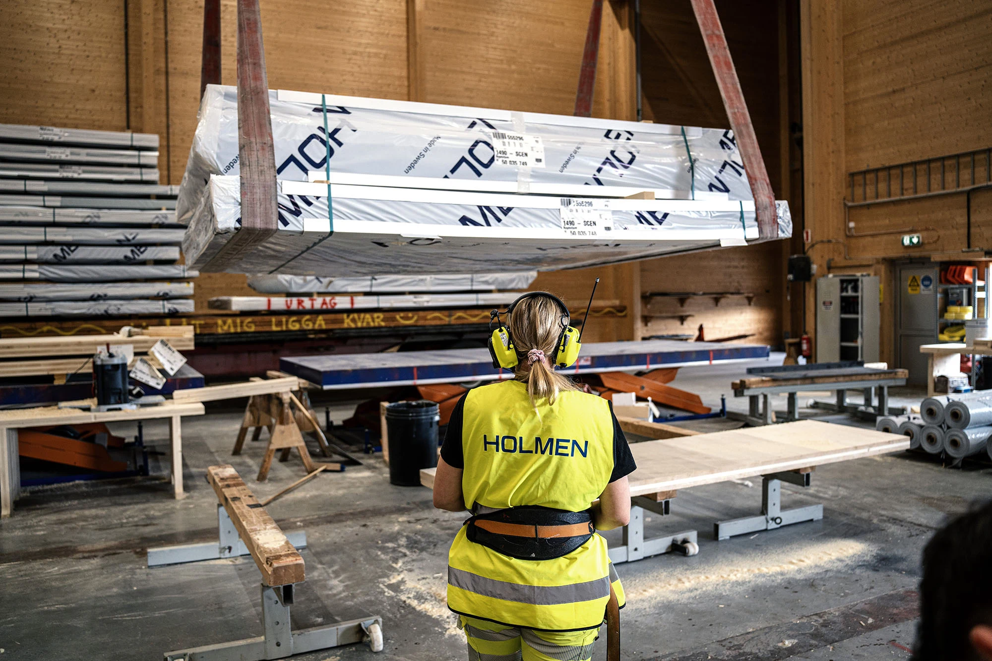 Holmen-medarbetare i varselkläder framför en hög med trävaror.