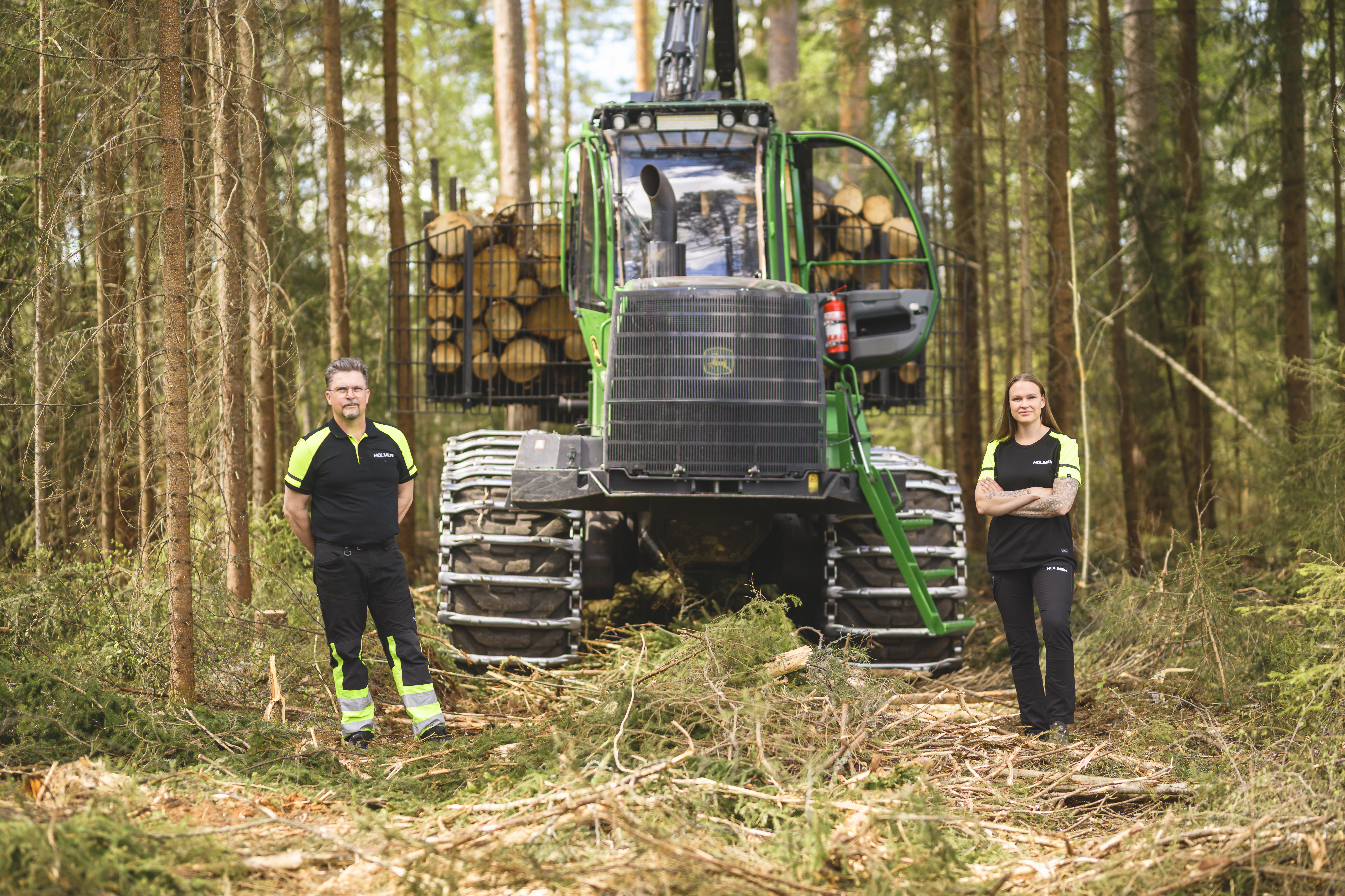 Medarbetare från Holmen Skog står framför en skogsmaskin
