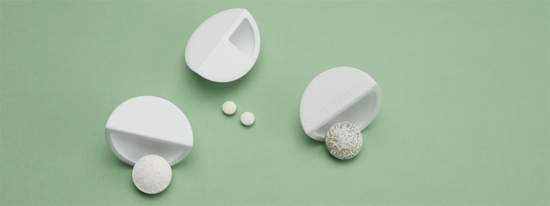 White wood-based packaging with dissolvable tablets on green background